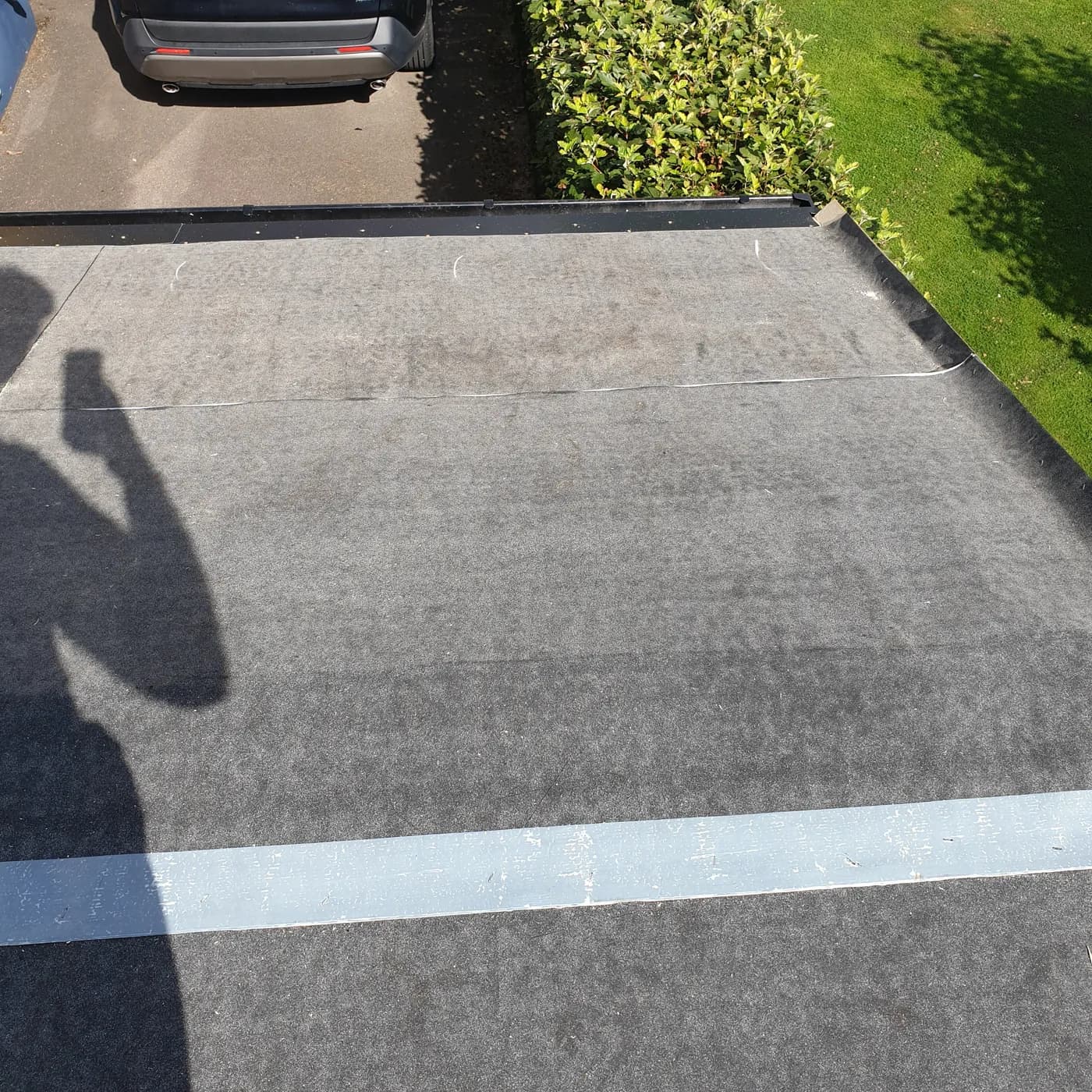 Ny svart takfotsplåt och ny hängränna monterade längs garagets framkant, med underlagspappen på plats.